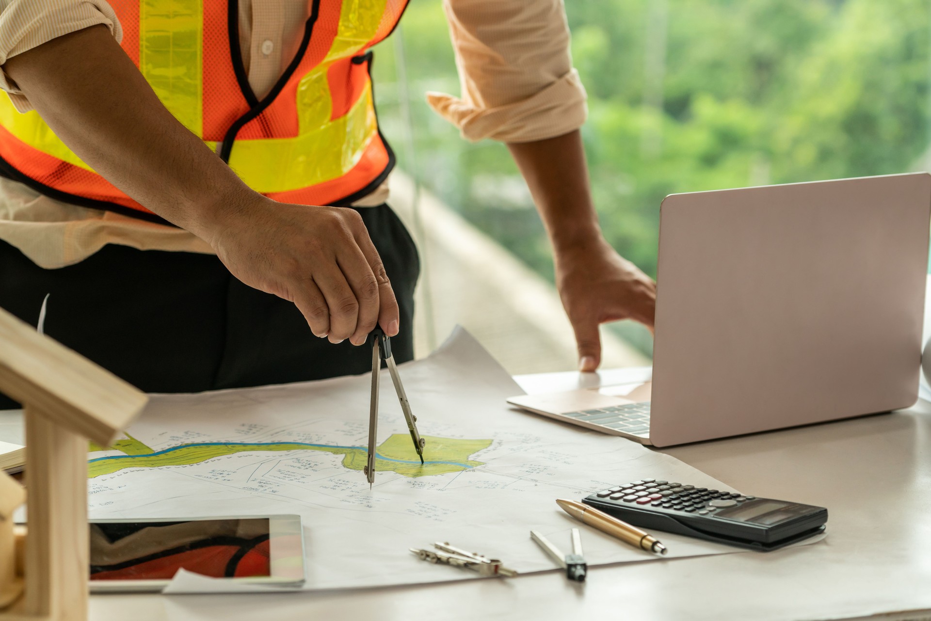 Young man architect or engineer working at desk with designer equipment to make interior design at workplace. Real estate business and civil engineering concept.